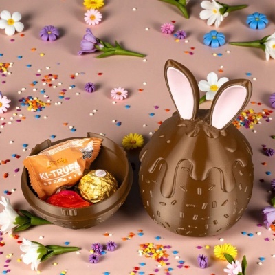Caixa de chocolate ovo coelho com doces, confetes e flores coloridas