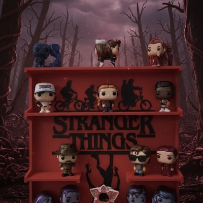 Expositor vermelho com figuras Funko Pop da série Stranger Things em floresta escura