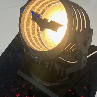 Holofote preto com luz amarela e silhueta de morcego no centro
