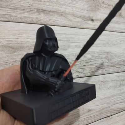 Figura negra de personagem com capacete e capa segurando espada em base preta