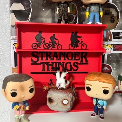 Figuras Funko Pop da série Stranger Things com suporte vermelho e caixas ao fundo.