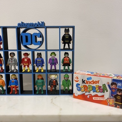 Expositor azul com figuras Playmobil DC e caixa Kinder Sorpresa ao lado