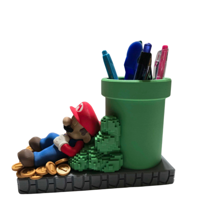 Porta-canetas verde com figura decorativa do Mario e moedas douradas numa base preta