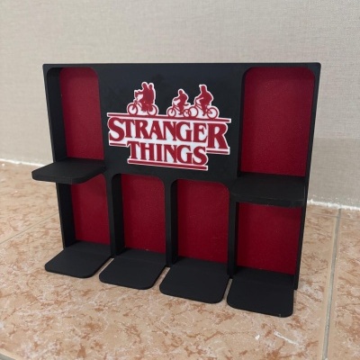 Expositor preto e vermelho com logotipo STRANGER THINGS e pequenas plataformas.