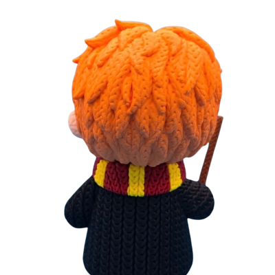 Figura de personagem com cabelo laranja, casaco preto, cachecol vermelho e amarelo, e varinha