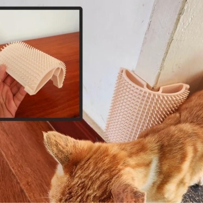 Escova de plástico cor de rosa clara para gatos com cerdas flexíveis junto a um gato laranja e cantos de parede