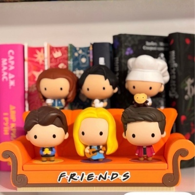 Figuras colecionáveis Funko Pop da série FRIENDS num sofá laranja