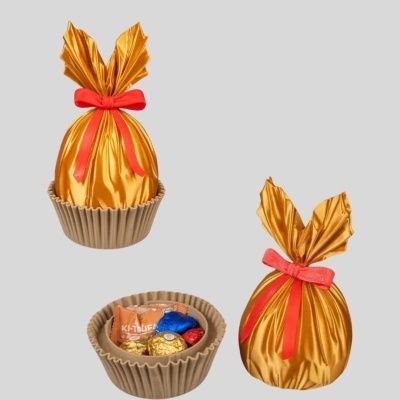 Três sacos dourados com laço vermelho em recipiente castanho com bombons