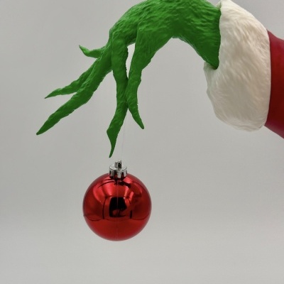 Mão verde segurando uma bola de Natal vermelha