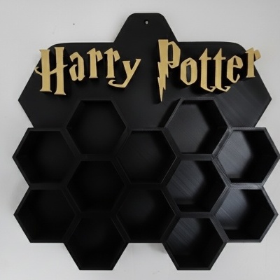 Prateleira de parede preta com forma de colmeia e texto Harry Potter em dourado no topo