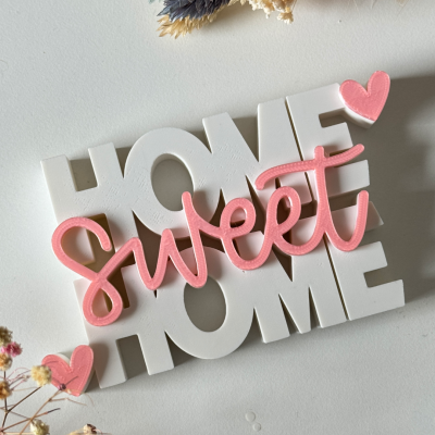 Decoração em forma de palavras HOME sweet HOME em madeira branca e rosa com corações, sobre fundo branco e flores secas.