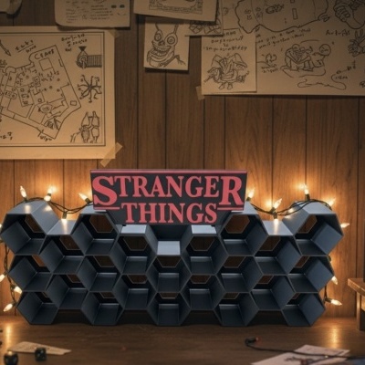 Prateleira hexagonal preta com luzes e placa Stranger Things, em ambiente retro com televisão antiga e desenhos na parede.