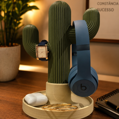 Suporte organizador cacto verde com relógio, headphones, auriculares e pulseiras numa mesa