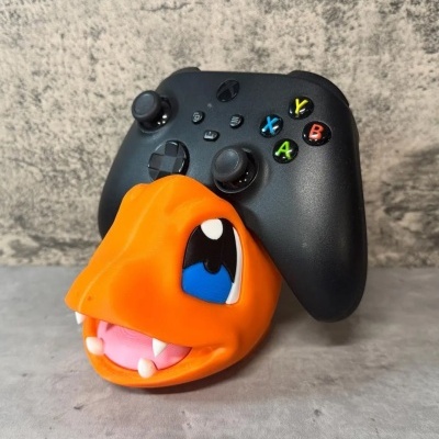 Comando de videojogo preto com suporte em forma de cabeça de dinossauro laranja