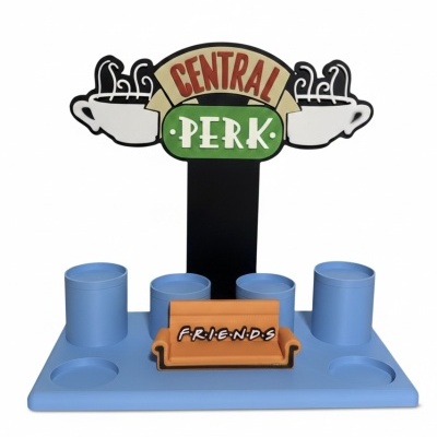 Suporte azul para copos com letreiro Central Perk e sofá laranja com texto Friends