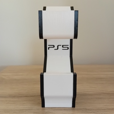 Suporte impresso em 3D branco e preto com texto PS5 numa superfície de madeira