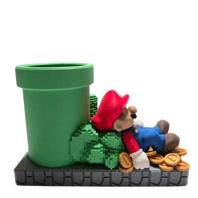 Figura de Super Mario a descansar encostado a um cano verde com moedas à volta.