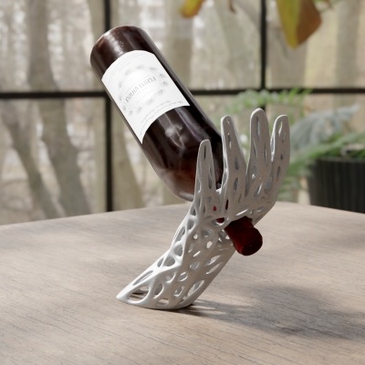 Garrafa castanha com rótulo branco numa base decorativa branca em forma de mão sobre mesa de madeira