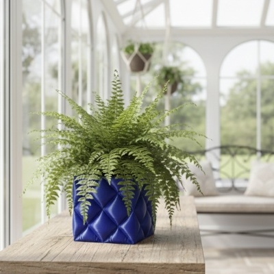Vaso azul acolchoado com planta verde numa mesa de madeira