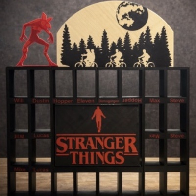Expositor preto de madeira com texto Stranger Things e figuras e nomes relacionados à série.