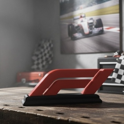 Modelo do logótipo da Fórmula 1 em plástico vermelho sobre mesa de madeira rústica com decoração de automobilismo