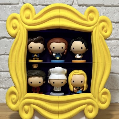 Caixa amarela em forma de moldura com seis figuras de vinil dentro.