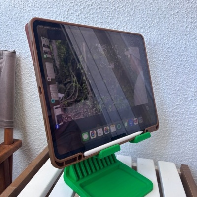 Tablet com capa castanha num suporte verde sobre uma mesa branca exterior