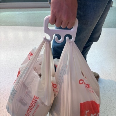 Mão a segurar suporte branco com sacos de plástico do supermercado Continente