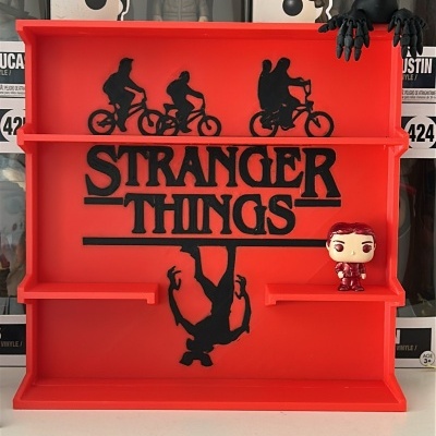 Estante vermelha Stranger Things com figuras Funko Pop e caixas ao fundo.