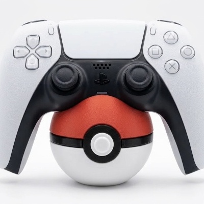 Comando de jogo sem fios branco e preto apoiado numa Pokébola