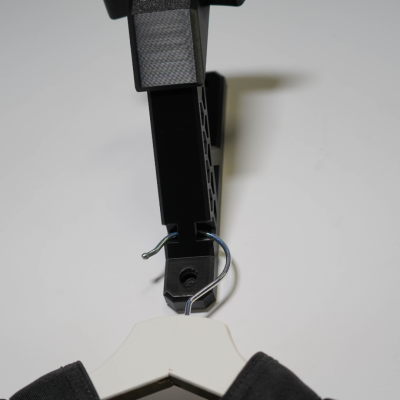 Suporte de parede preto com gancho metálico a segurar cabide branco com roupa preta