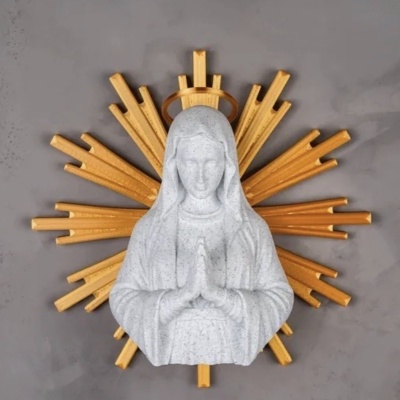 Escultura branca de figura religiosa com mãos em oração e halo dourado com raios fundo cinzento