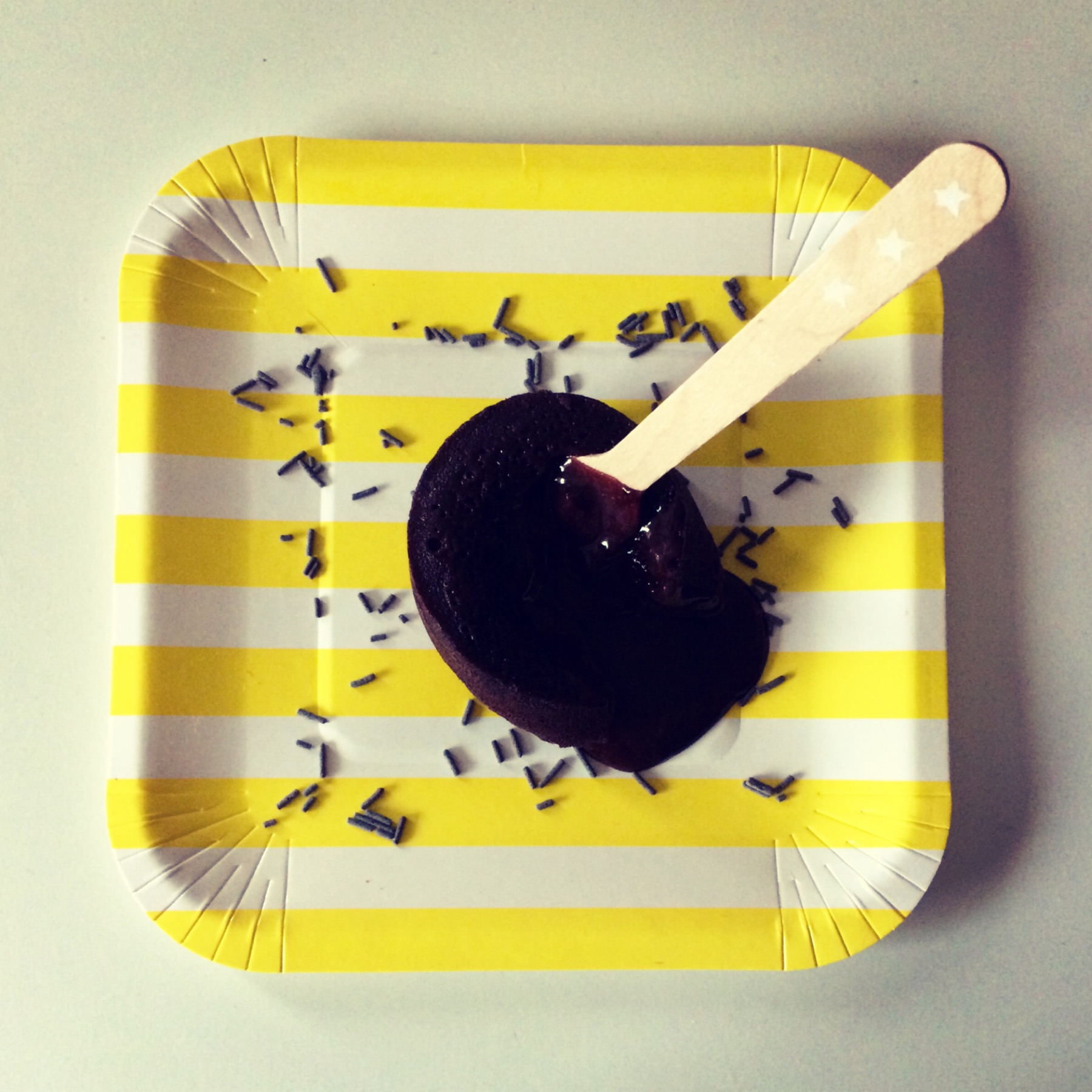 Gelado de chocolate num prato de papel com riscas amarelas e brancas