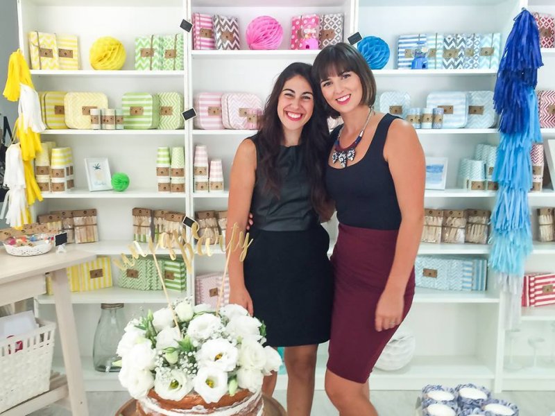 Duas mulheres em loja com produtos em embalagens brancas e coloridas nas prateleiras