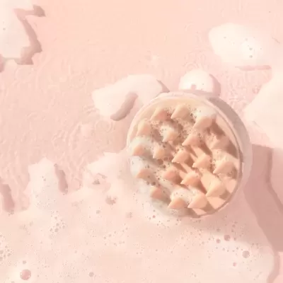 bebida espumosa em copo transparente sobre superfície rosa com espuma