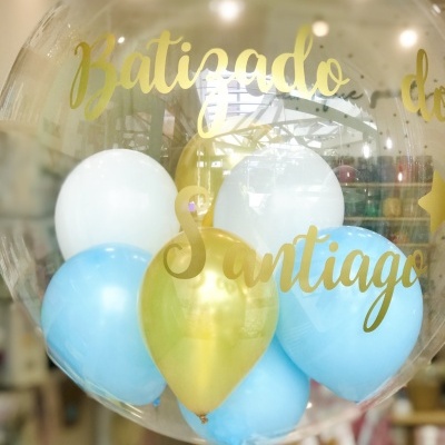 Balão transparente com balões azuis, brancos e dourados e texto dourado em interior