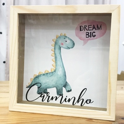 Quadro decorativo em madeira com ilustração de dinossauro e texto 'DREAM BIG' e 'Carminho'