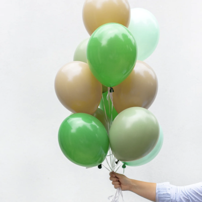 Ramo de balões verdes e beges segurado por uma mão