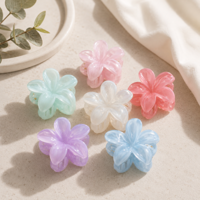 Seis molas de cabelo em forma de flor em cores pastel sobre superfície clara