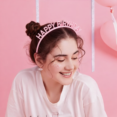 Mulher sorridente com tiara HAPPY BIRYHDAY e fundo rosa com balões
