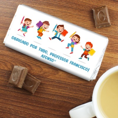 Barra de chocolate embrulhada com desenho de crianças e texto de agradecimento para professor sobre madeira