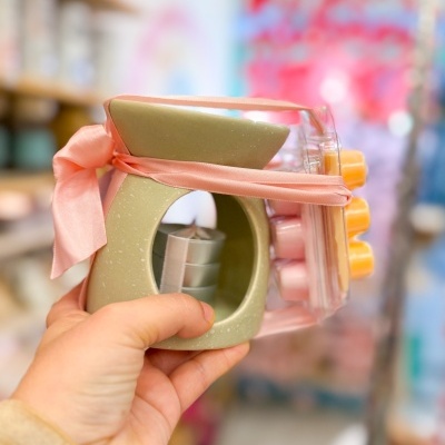 Queimador de óleo cerâmico verde claro com velas aromáticas cor de pêssego e fita rosa