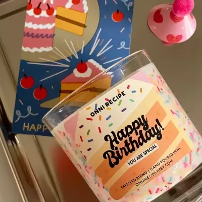 Vela de aniversário com rótulo de bolo, cartão ilustrado com fatias de bolo e chapéu de festa rosa com pompom