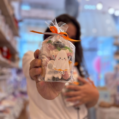 Pacote transparente com doces coloridos e adesivo de fantasma sorridente com laço laranja