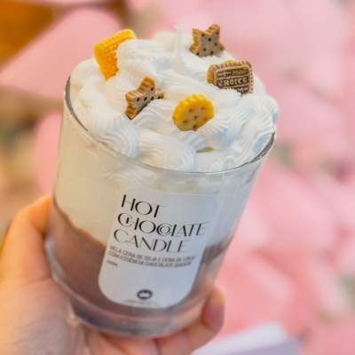 Vela decorativa imitando chocolate quente com chantili e bolachas em copo de vidro