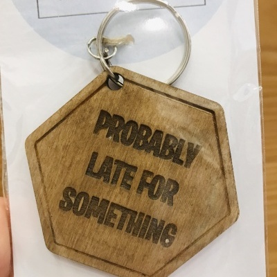 porta-chaves em madeira hexagonal com texto gravado 'PROBABLY LATE FOR SOMETHING'