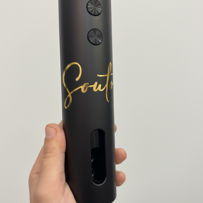 Dispositivo preto com botões e texto dourado Souto na mão