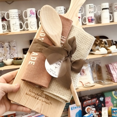 Conjunto de utensílios de cozinha com tábua de madeira e panos de prato amarrados com fita