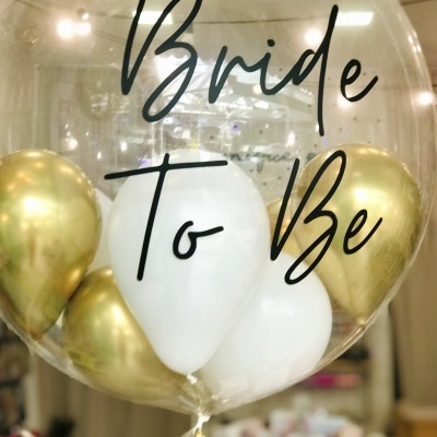 Balão transparente com texto 'Bride To Be' e balões pequenos dourados e brancos dentro