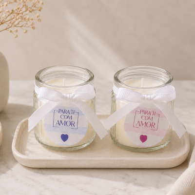 Duas velas em recipientes de vidro com laços brancos e etiquetas PARA TI COM AMOR em azul e rosa